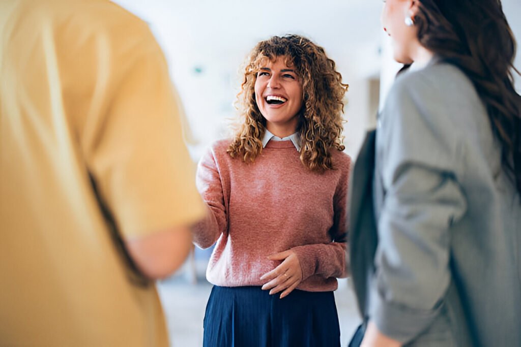 Smiling individuals interact and enjoy casual conversation in a welcoming professional atmosphere, promoting positivity and collaboration illustrating talent sourcing strategies